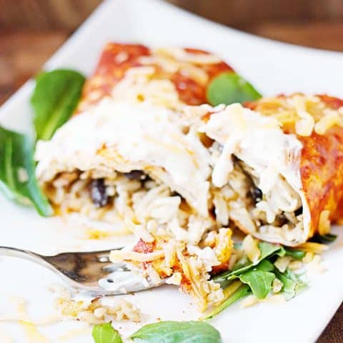 Enchilada style burritos feature enchilada sauce, dirty rice, and a versatile recipe that makes enough for two 9x13-inch pans. That means you can bake one tonight and freeze one for a future Taco Tuesday! | halfscratched.com #burrito #enchiladas #freezermeal #mexican #mexicanfood #mexicanrecipe #tacotuesday #cincodemayo