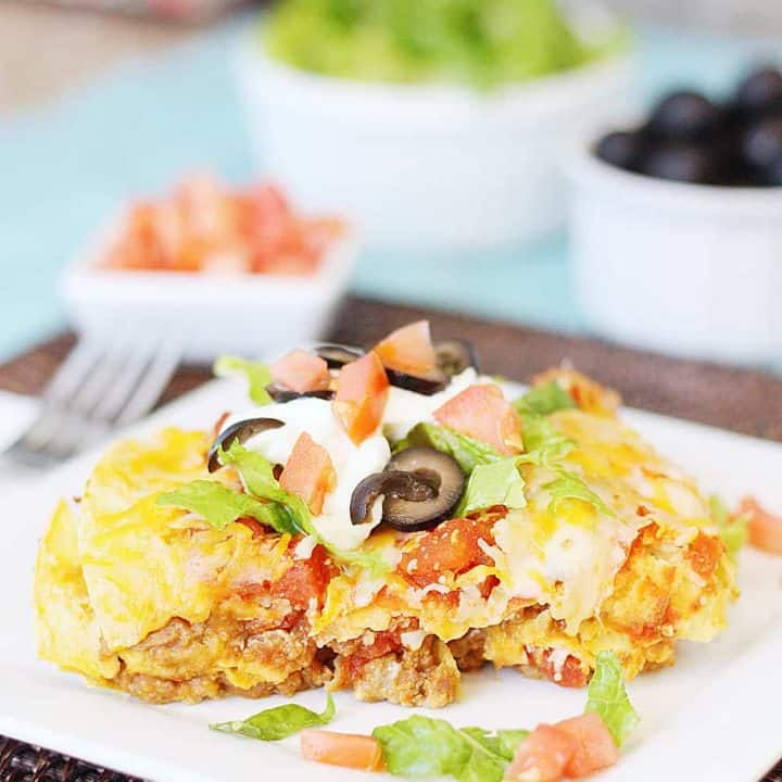 Mexican Lasagna -- Mexican lasagna features layers of tortillas, taco meat, refried beans, salsa, cheese, and more cheese. Top with your favorite taco toppings and you have an easy weeknight Mexican recipe the entire family will love! #mexican #lasagna #tacotuesday #mexicanrecipe #easyrecipe