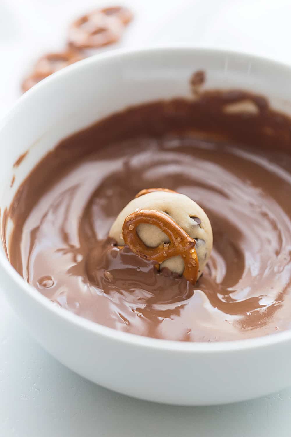 Cookie Dough Pretzel Bites dipping in chocolate.