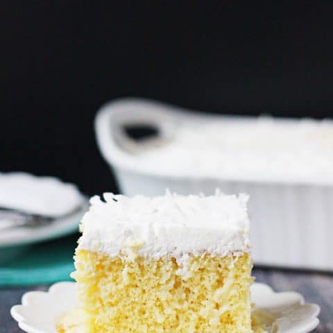 Coconut Poke Cake -- This coconut poke cake features a yellow cake infused with sweet coconut cream and topped with homemade whipped cream frosting and shredded coconut.