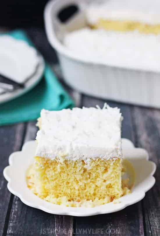 Coconut Poke Cake -- This coconut poke cake features a yellow cake infused with sweet coconut cream and topped with homemade whipped cream frosting and shredded coconut.