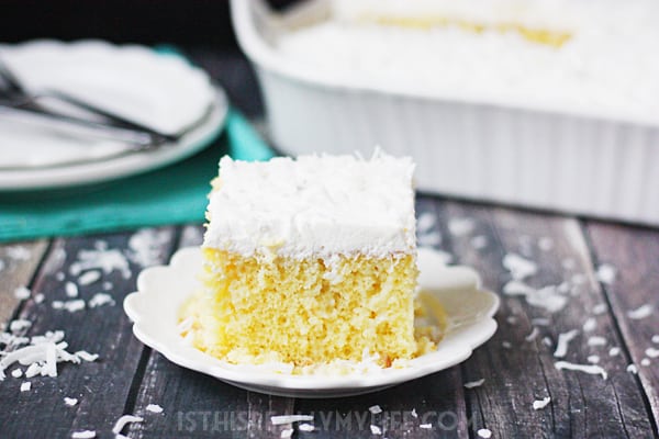 Coconut Poke Cake -- This coconut poke cake features a yellow cake infused with sweet coconut cream and topped with homemade whipped cream frosting and shredded coconut.