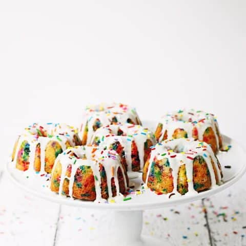 Mini Funfetti Bundt Cake with Vanilla Glaze -- Mini funfetti bundt cakes with vanilla glaze are a fun party dessert. Perfect topped with a scoop of ice cream, whipped cream, more sprinkles and a cherry! | halfscratched.com