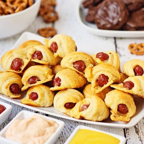 Cheesy Pigs in a Blanket + Sweet Sriracha Dipping Sauce -- After tasting these cheesy pigs in a blanket with sweet sriracha dipping sauce, you'll want to serve them at every game day party! | halfscratched.com