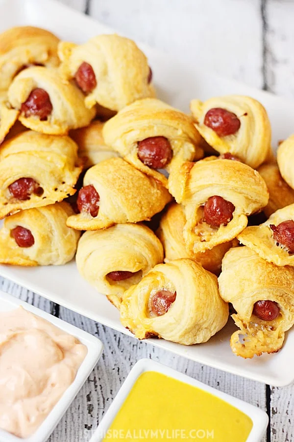 Cheesy Pigs in a Blanket + Sweet Sriracha Dipping Sauce -- After tasting these cheesy pigs in a blanket with sweet sriracha dipping sauce, you'll want to serve them at every game day party! | halfscratched.com