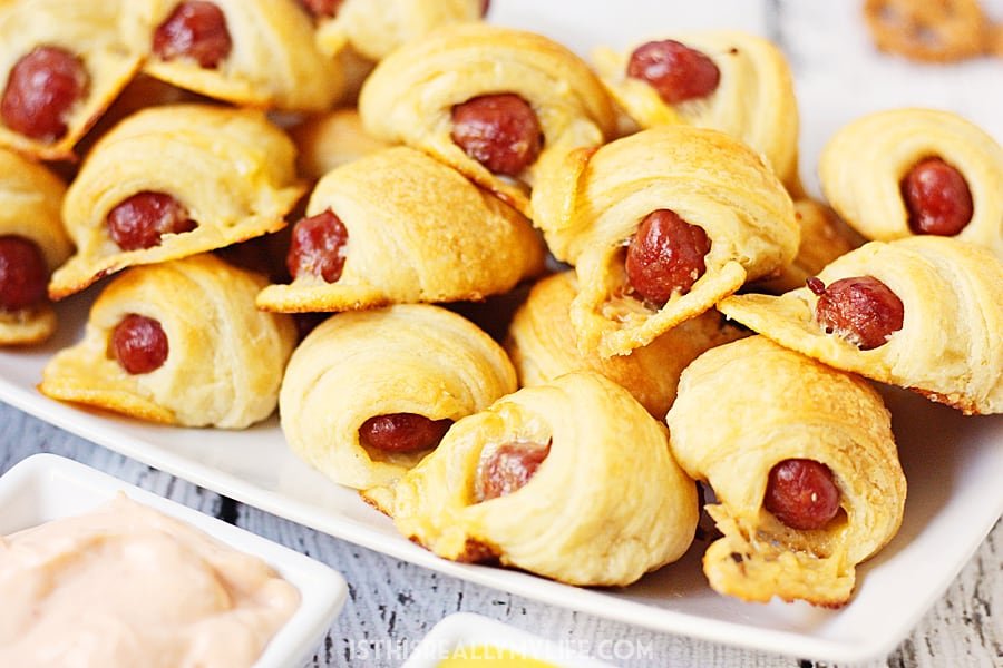 Cheesy Pigs in a Blanket + Sweet Sriracha Dipping Sauce -- After tasting these cheesy pigs in a blanket with sweet sriracha dipping sauce, you'll want to serve them at every game day party! | halfscratched.com
