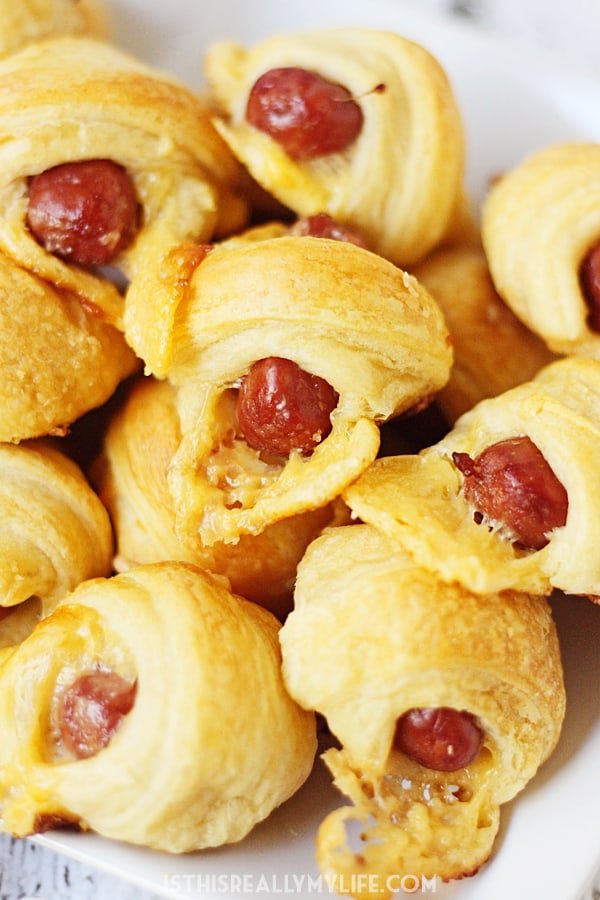 Cheesy Pigs in a Blanket + Sweet Sriracha Dipping Sauce -- After tasting these cheesy pigs in a blanket with sweet sriracha dipping sauce, you'll want to serve them at every game day party! | halfscratched.com