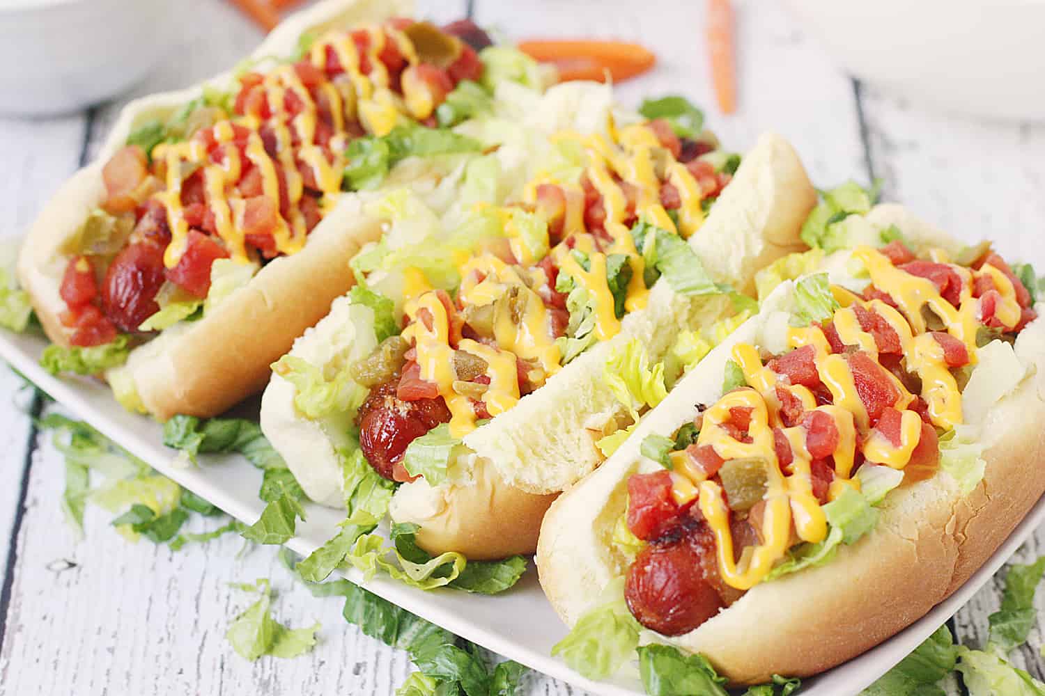 Spicy Bacon-Wrapped BLT Dogs -- Making bacon-wrapped hot dogs in the oven is easier than you think! Try this simple technique for bacon hot dogs as you throw together a batch of these spicy BLT dogs drizzled with melted cheese sauce. #halfscratched #hotdogs #blt #bacon #easyrecipe #maindish #bbq #barbecue #grilling