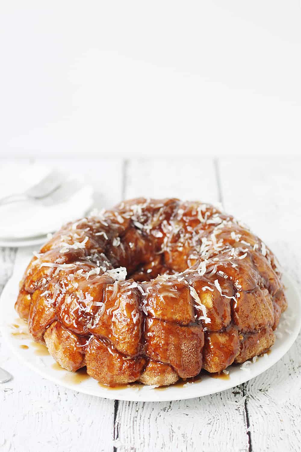 Easy Coconut Caramel Monkey Bread -- You'll want to lick every finger after eating this easy coconut caramel monkey bread! Pull-apart, cinnamon-coated bread is covered in gooey caramel sauce and sprinkled with sweet shredded coconut. It's to die for! #halfscratched #monkeybread #bread #dessert #easyrecipe #coconut #caramel