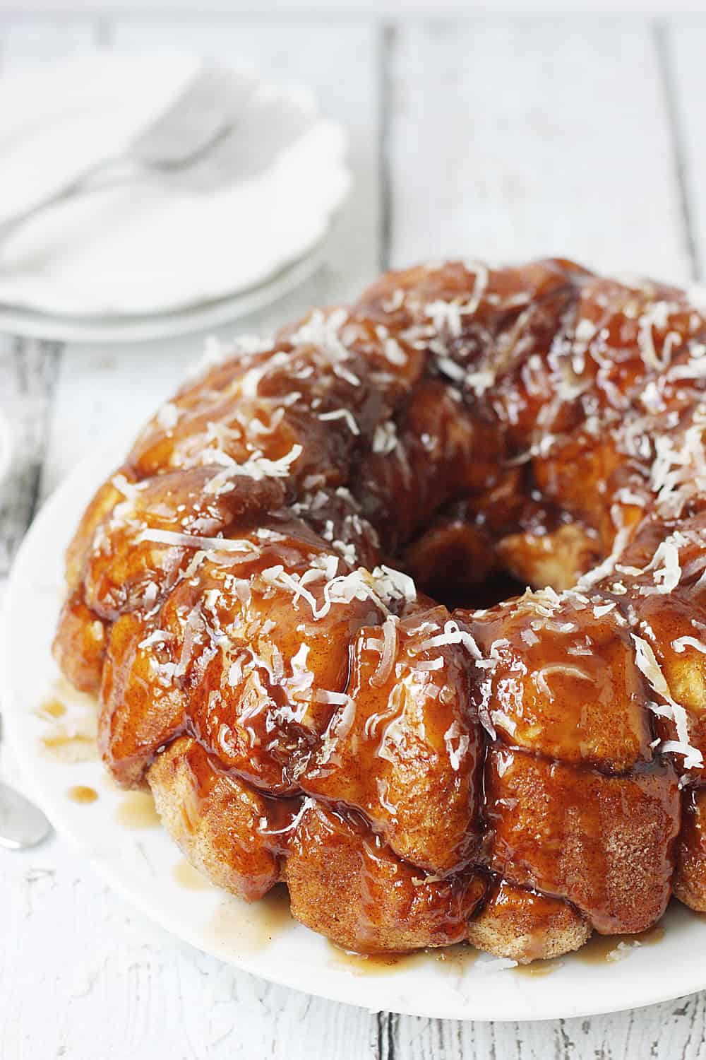 Easy Coconut Caramel Monkey Bread -- You'll want to lick every finger after eating this easy coconut caramel monkey bread! Pull-apart, cinnamon-coated bread is covered in gooey caramel sauce and sprinkled with sweet shredded coconut. It's to die for! #halfscratched #monkeybread #bread #dessert #easyrecipe #coconut #caramel