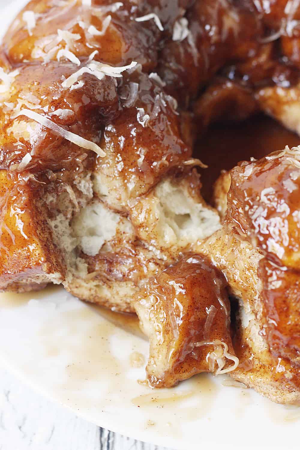 Easy Coconut Caramel Monkey Bread -- You'll want to lick every finger after eating this easy coconut caramel monkey bread! Pull-apart, cinnamon-coated bread is covered in gooey caramel sauce and sprinkled with sweet shredded coconut. It's to die for! #halfscratched #monkeybread #bread #dessert #easyrecipe #coconut #caramel