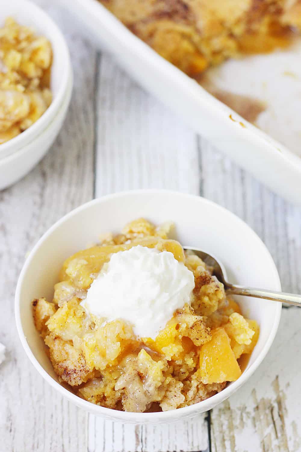 Easy Peach Cobbler Dump Cake -- Easy peach cobbler dump cake is sure to become a summer staple! This mouthwatering peach cobbler recipe requires only four ingredients and five minutes of prep! #cake #peachcobbler #dumpcake #dessert #easyrecipe #cakemix #cobbler #peach