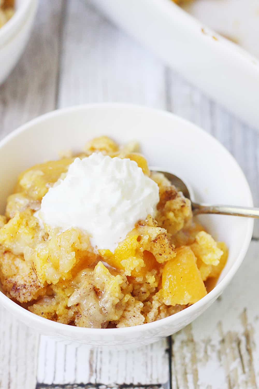 Easy Peach Cobbler Dump Cake -- Easy peach cobbler dump cake is sure to become a summer staple! This mouthwatering peach cobbler recipe requires only four ingredients and five minutes of prep! #cake #peachcobbler #dumpcake #dessert #easyrecipe #cakemix #cobbler #peach