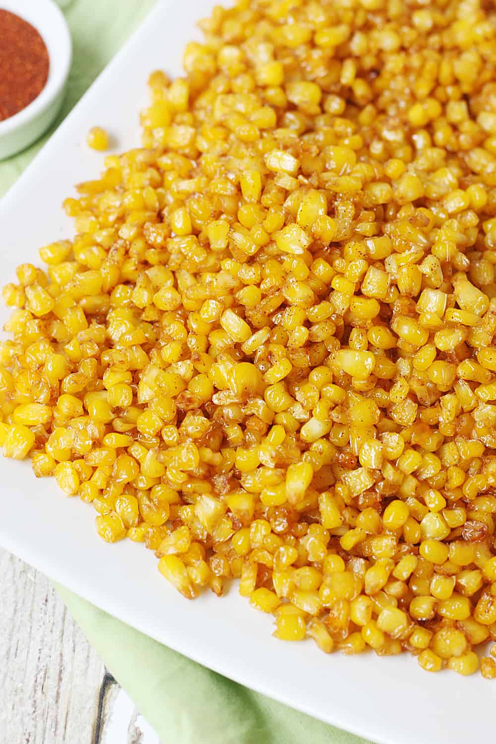 Roasted corn on a plate with a spoon close-up.