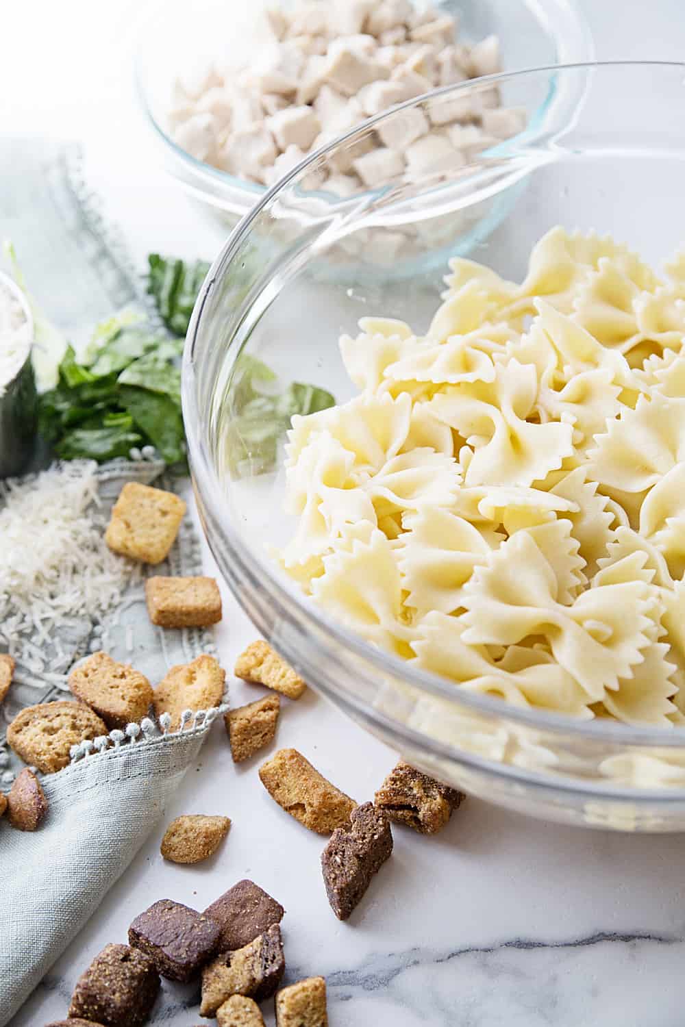 Best Bowtie Chicken Caesar Salad - There's chicken Caesar salad and there's chicken Caesar pasta salad. Once you add bowtie pasta to Caesar salad, you won't want to eat it any other way! #caesarsalad #bowtie #pastasalad #pasta #salad #halfscratched #easyrecipe #sidedish