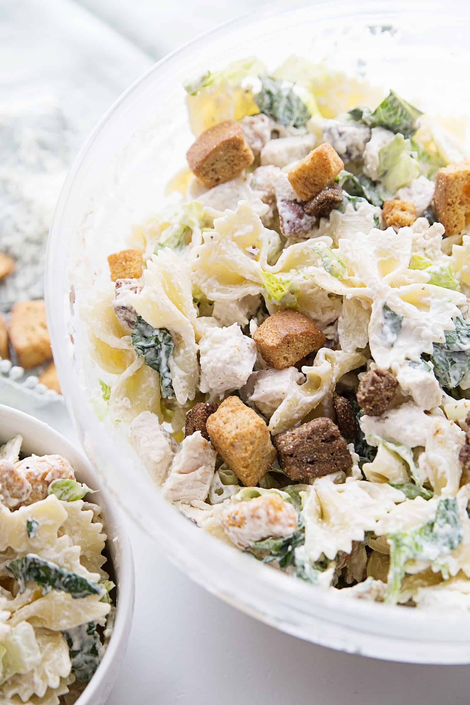 Best Bowtie Chicken Caesar Salad - There's chicken Caesar salad and there's chicken Caesar pasta salad. Once you add bowtie pasta to Caesar salad, you won't want to eat it any other way! #caesarsalad #bowtie #pastasalad #pasta #salad #halfscratched #easyrecipe #sidedish