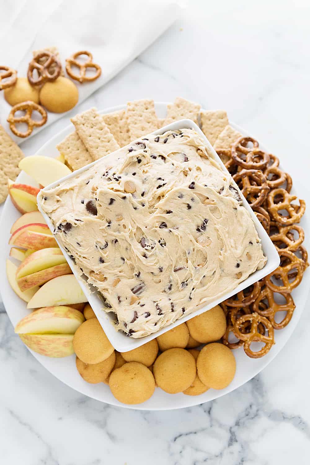 Peanut Butter Cookie Dough Dip with apple slices and pretzels.