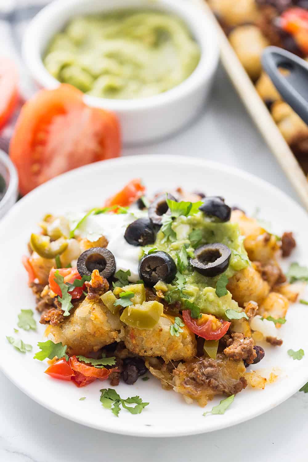 Tater Tot Nachos (Totchos) - What's better than crispy, crunch tater tots topped with oh-so-flavorful nacho fixings? Nothing! That's why tater tot nachos, aka totchos, are always a hit! #nachos #tatertots #tatertotcasserole #appetizer #baking #cooking #easyrecipe #halfscratched #tatertotnachos #mexicanfood