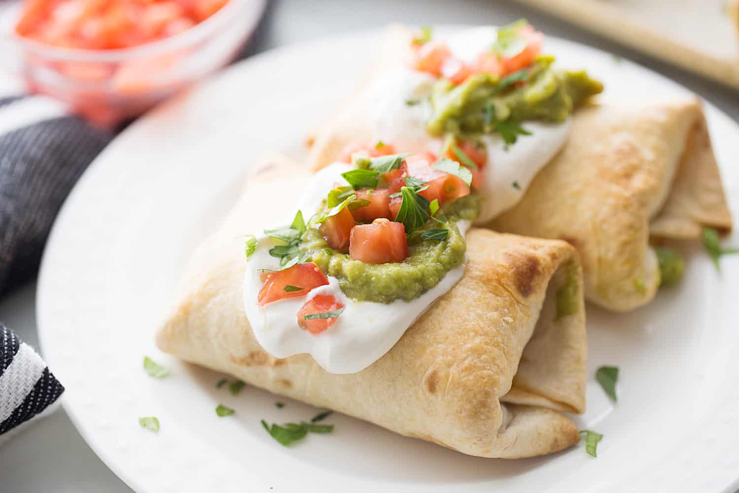 Baked Chicken Chimichangas - Baked chicken chimichangas make for a fun, flavorful alternative to tacos for Taco Tuesday. They're also a super tasty freezer meal! #mexicanrecipe #mexicanfood #chimichangas #easyrecipe #freezermeal #freezerrecipe #halfscratched #tacotuesday