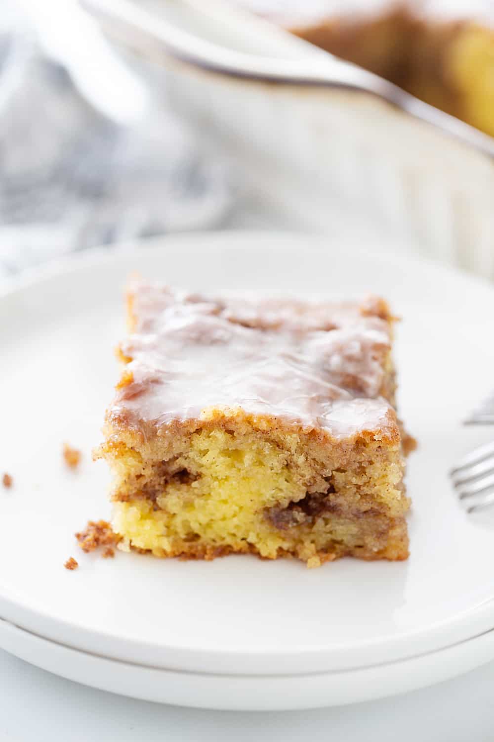 There's nothing like hot, cinnamon-swirled yellow cake topped with powdered sugar icing. Dessert or breakfast? Honey bun cake is both! #honeybun #cinnamonroll #cakemix #cakemixrecipe #honeybuncake #baking #dessert #brunch #halfscratched #yellowcake #easyrecipe