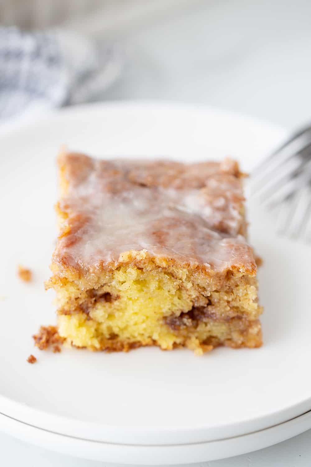 There's nothing like hot, cinnamon-swirled yellow cake topped with powdered sugar icing. Dessert or breakfast? Honey bun cake is both! #honeybun #cinnamonroll #cakemix #cakemixrecipe #honeybuncake #baking #dessert #brunch #halfscratched #yellowcake #easyrecipe