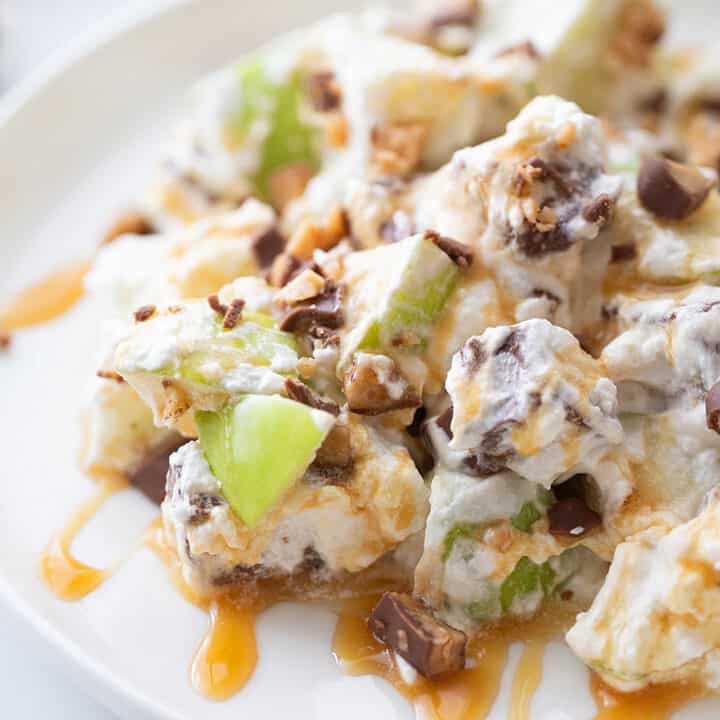 Easy Snickers Salad - This easy Snickers salad features Granny Smith apples, Snickers, and whipped topping with a drizzle of caramel and a sprinkle of toffee bits. #snickers #salad #dessert #halfscratched #easyrecipe #dessertsalad #sweets