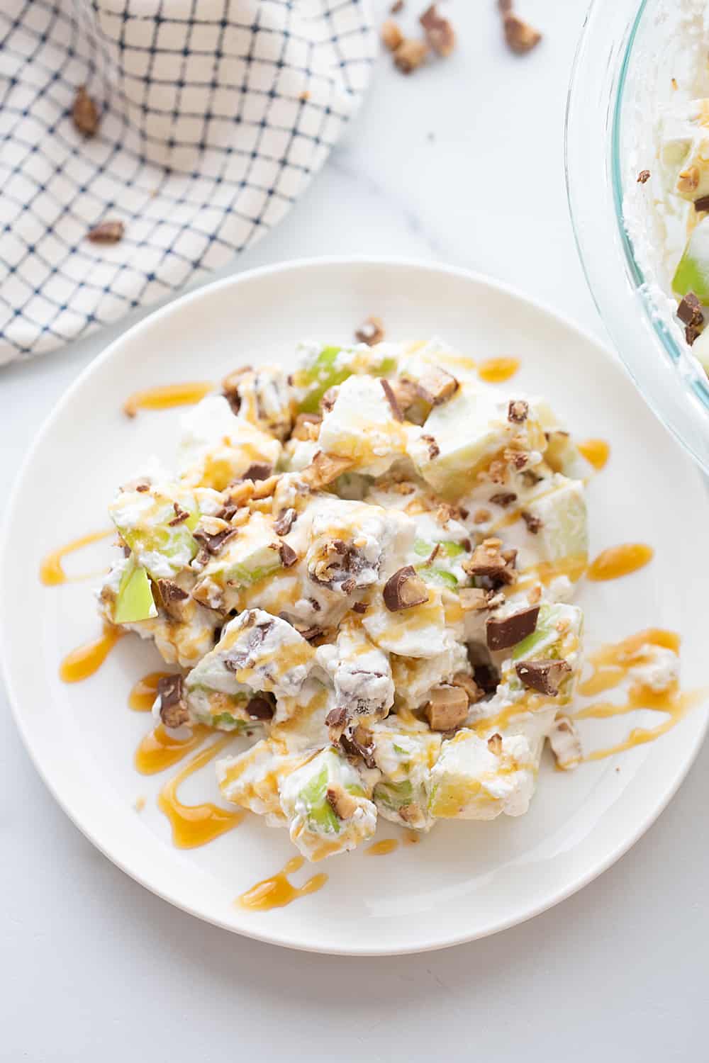 Easy Snickers Salad - This easy Snickers salad features Granny Smith apples, Snickers, and whipped topping with a drizzle of caramel and a sprinkle of toffee bits. #snickers #salad #dessert #halfscratched #easyrecipe #dessertsalad #sweets