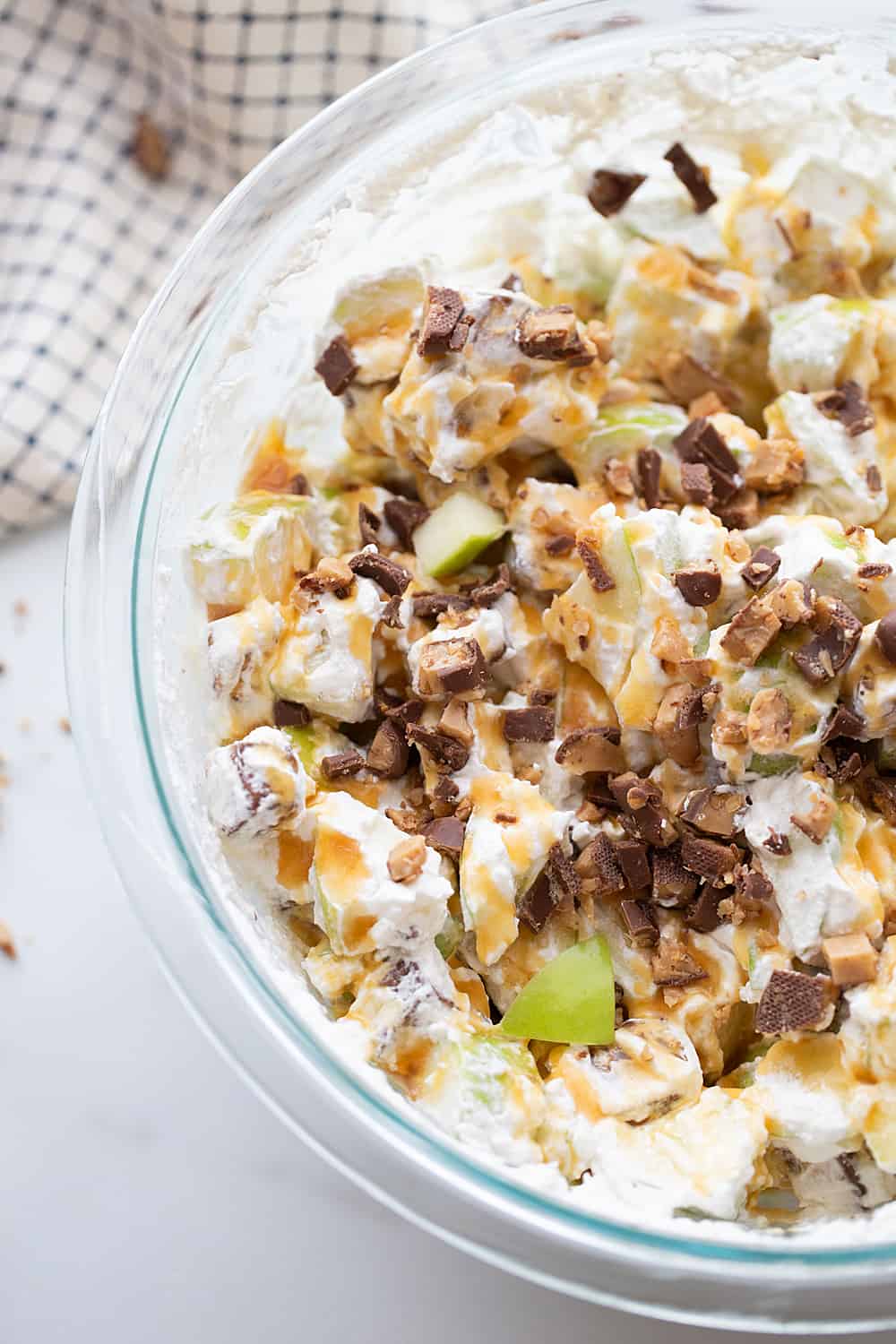 Easy Snickers Salad - This easy Snickers salad features Granny Smith apples, Snickers, and whipped topping with a drizzle of caramel and a sprinkle of toffee bits. #snickers #salad #dessert #halfscratched #easyrecipe #dessertsalad #sweets