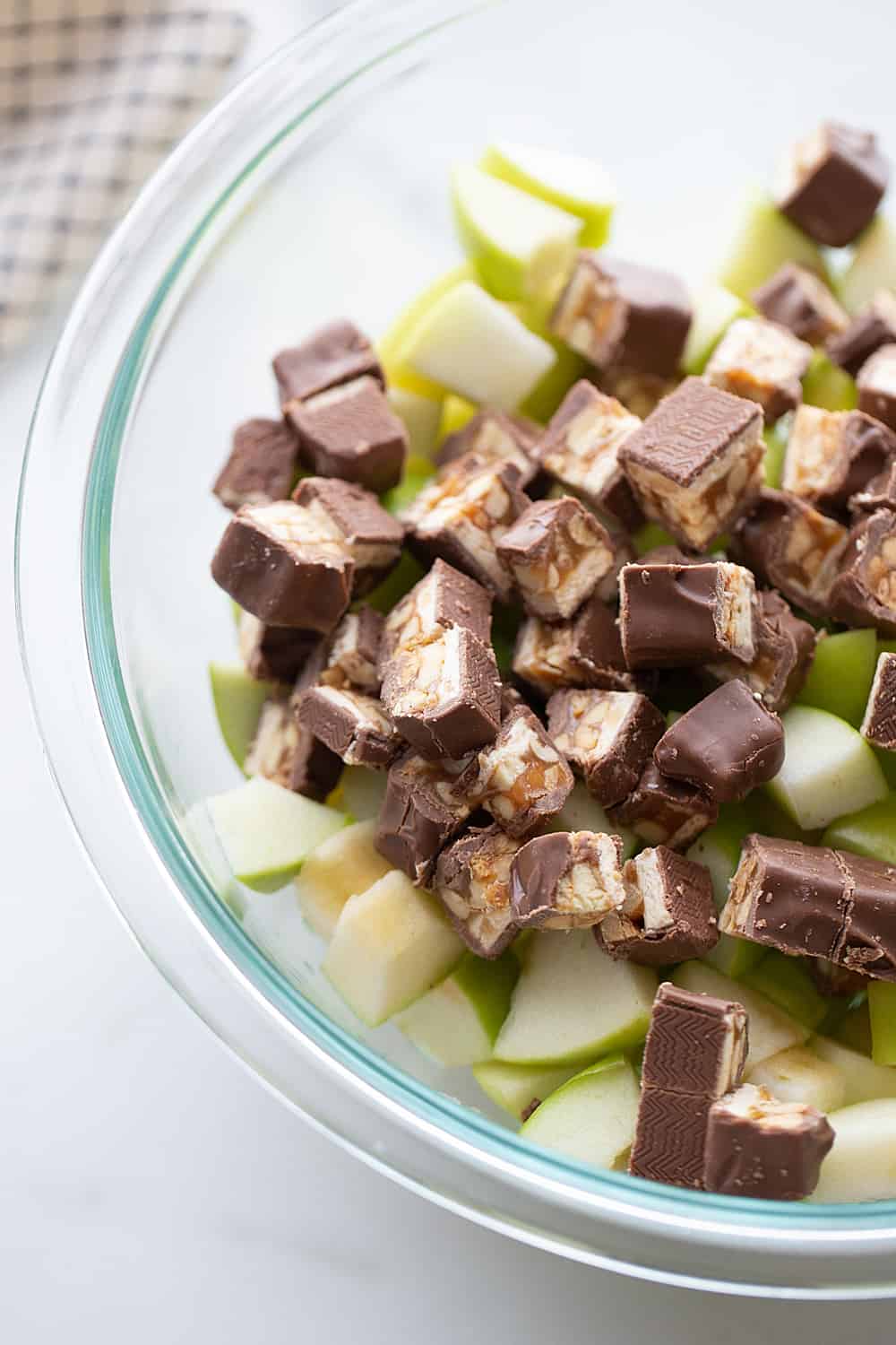 Easy Snickers Salad - This easy Snickers salad features Granny Smith apples, Snickers, and whipped topping with a drizzle of caramel and a sprinkle of toffee bits. #snickers #salad #dessert #halfscratched #easyrecipe #dessertsalad #sweets