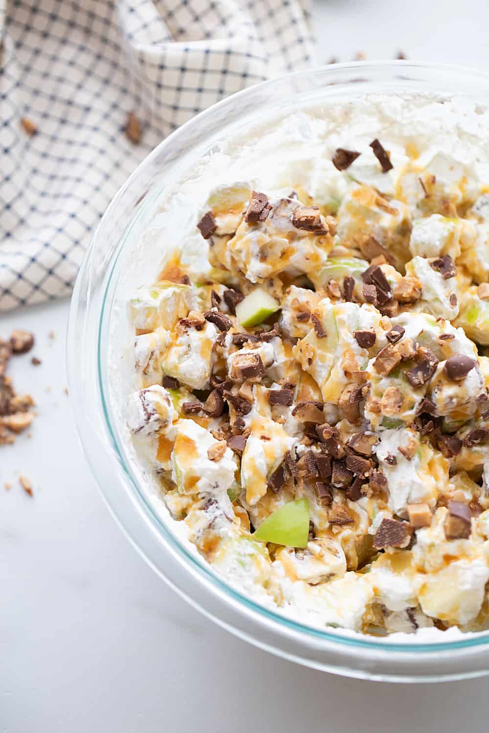 Easy Snickers Salad - This easy Snickers salad features Granny Smith apples, Snickers, and whipped topping with a drizzle of caramel and a sprinkle of toffee bits. #snickers #salad #dessert #halfscratched #easyrecipe #dessertsalad #sweets