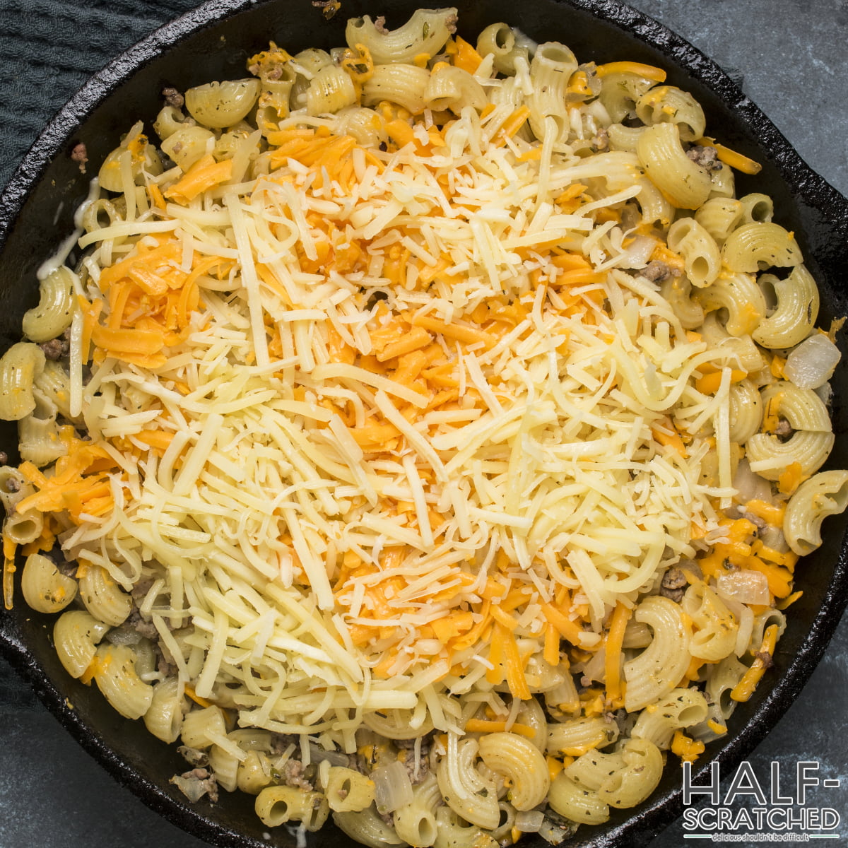 Adding mozzarella and cheddar to macaroni and meat