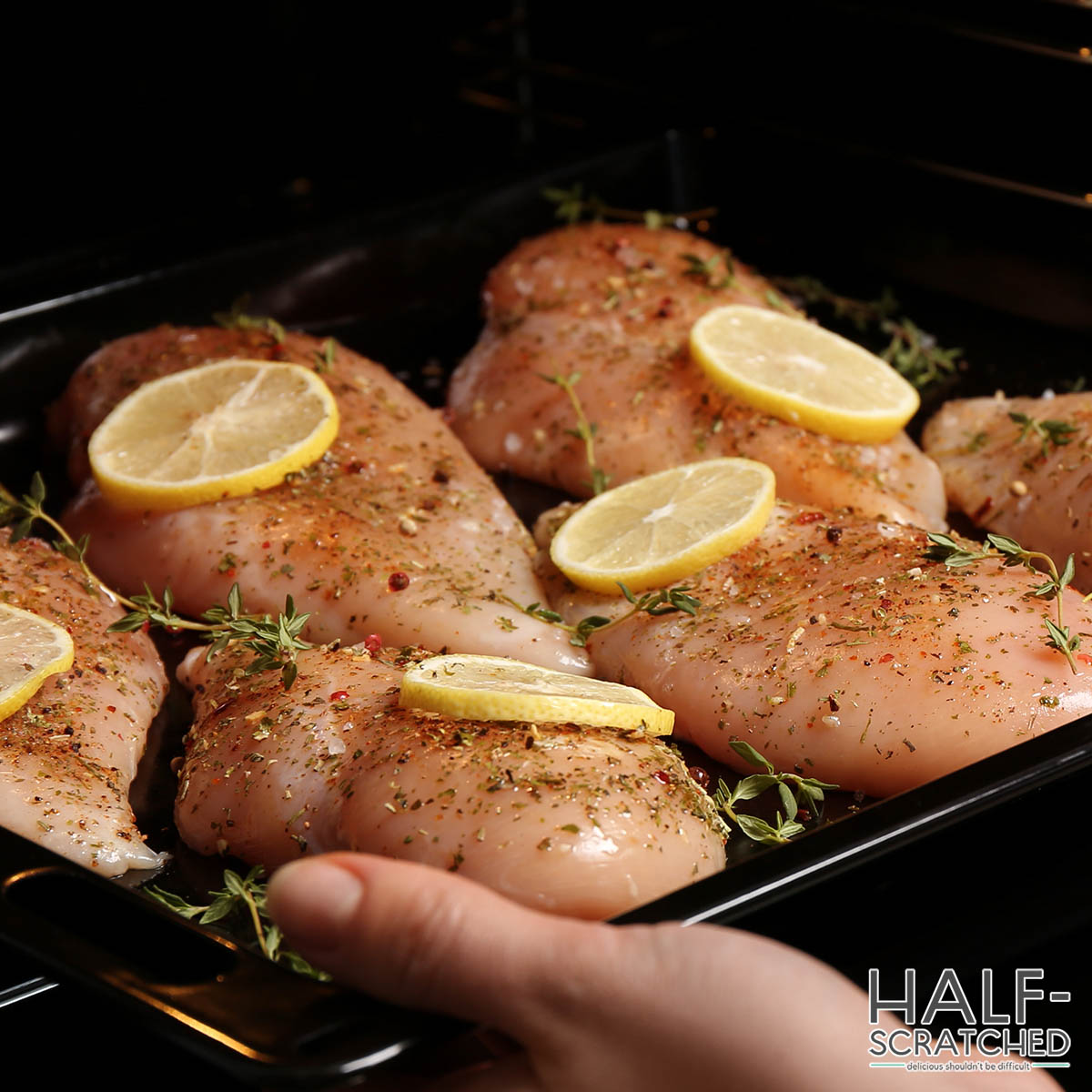 Woman putting chicken breast into oven