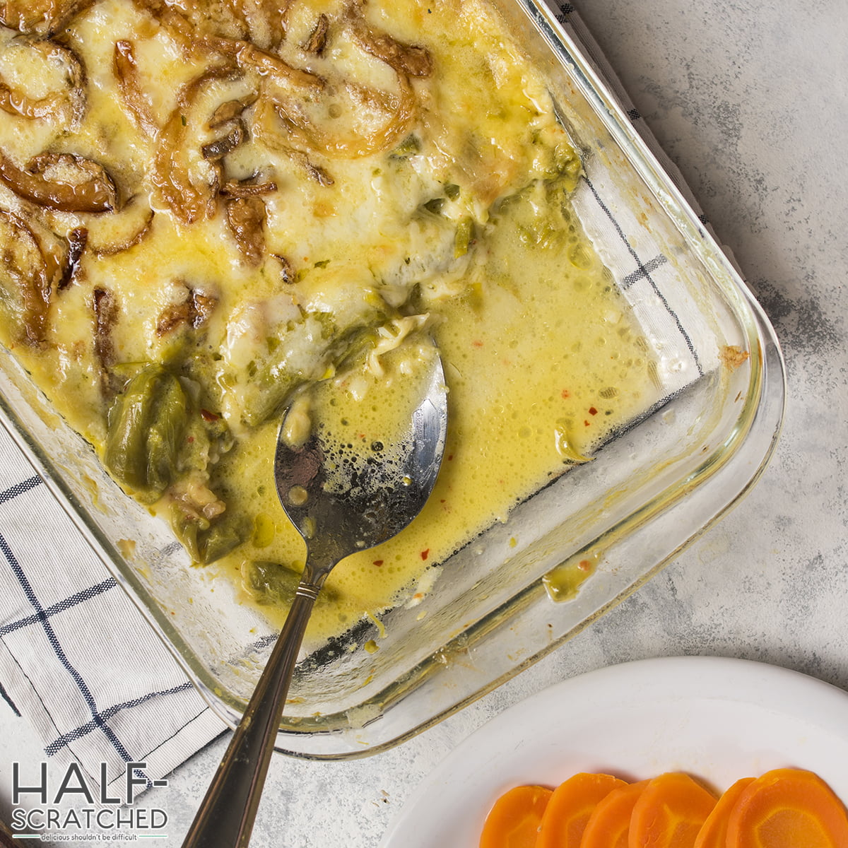 A baking tray with a spoon and baked asparagus with cheese