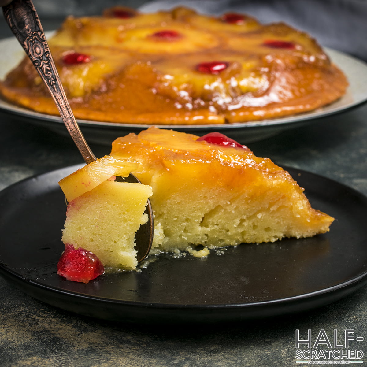 A spoon cutting a portion of pineapple upside down cake
