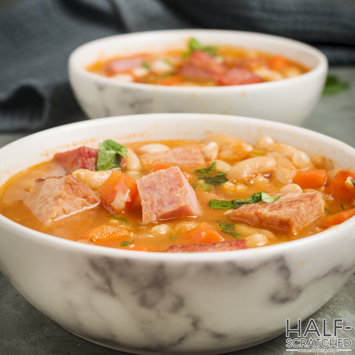 A white bowl with ham and bean soup