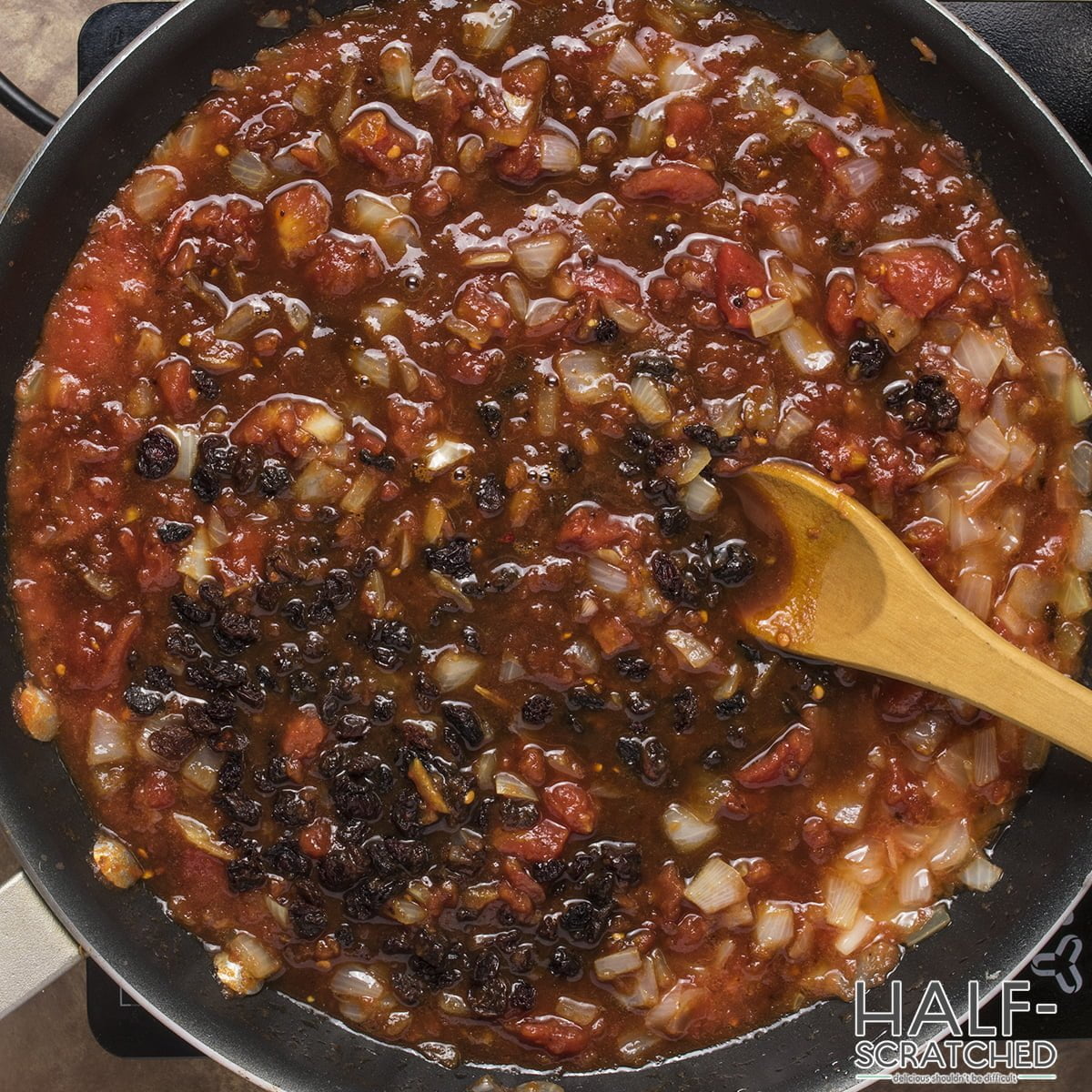 adding tomatoes, vinegar, brown sugar, raisins, salt, and pepper.