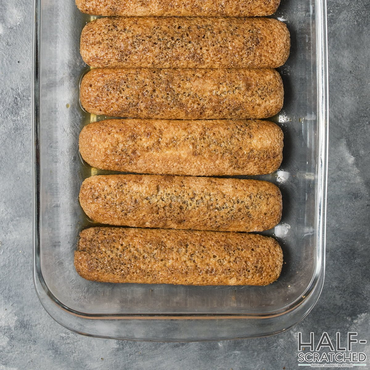 Arranging ladyfingers across the bottom of a baking dish"