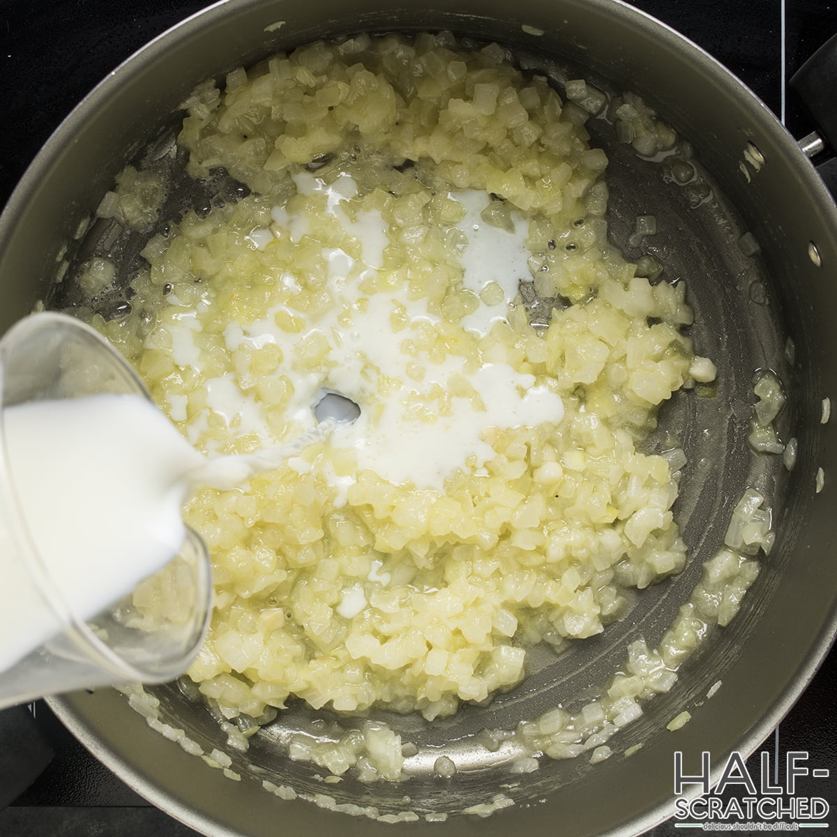 Adding milk to a mixture of onion and flour