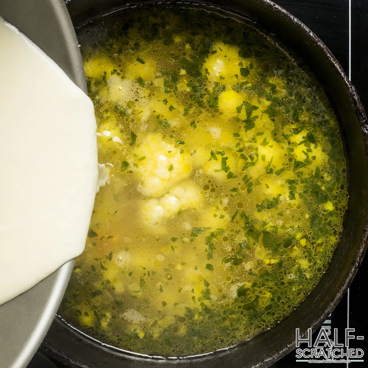 Pouring the cream mixture into a cauliflower soup mixture