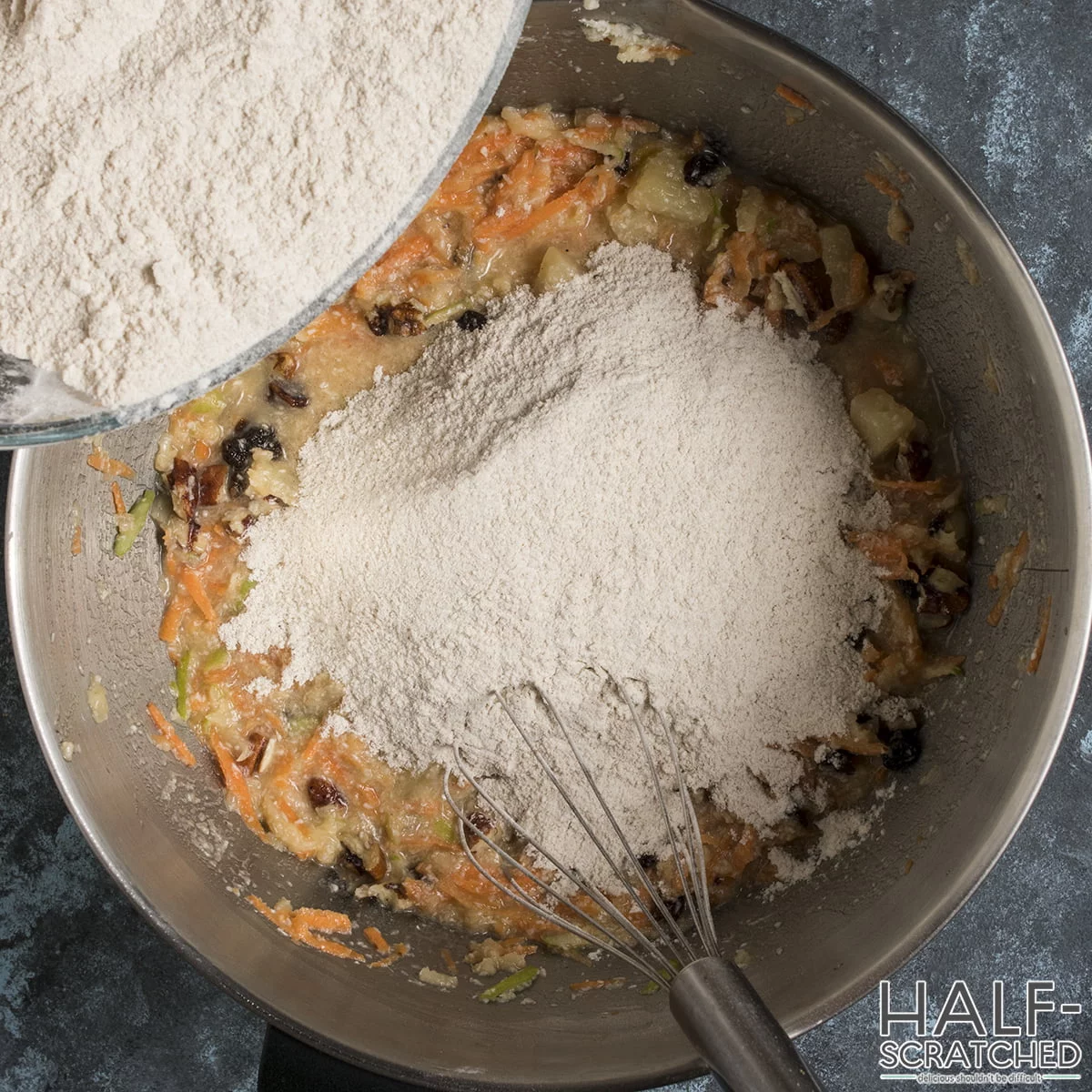 Dry ingredients being added to the wet mixture for morning glory muffins